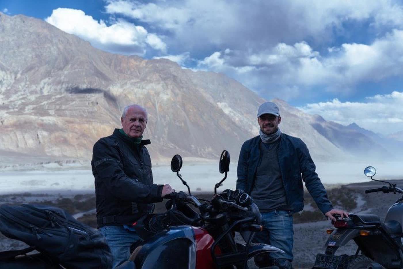 Two riders with their motorcycles beneath the mountains near Pangong